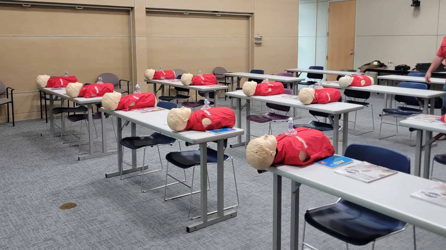 a friendly nurse instructor calmly coaching an adult student during CPR skills verification, Lafayette Louisiana, Cajun South Louisiana feel, professional training classroom, mannequins and AED trainers visible