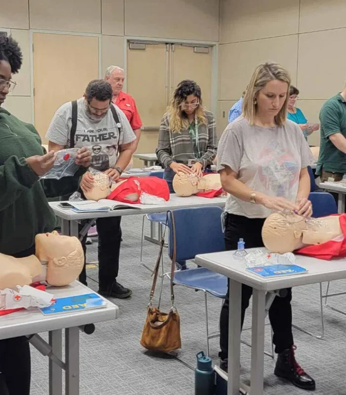 a friendly nurse instructor calmly coaching an adult student during CPR skills verification, Lafayette Louisiana, Cajun South Louisiana feel, professional training classroom, mannequins and AED trainers visible